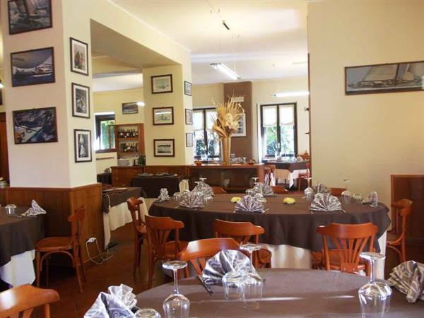 Restaurant dining room set with dark tablecloths, wooden chairs and sailboat paintings