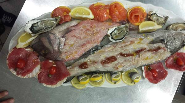 Raw seafood platter: whole sea bream, oysters, beef carpaccio and lemon slices