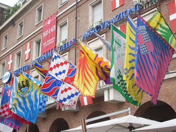 Colorful palio flags waving in front of the Istituto Nazionale delle Assicurazioni building