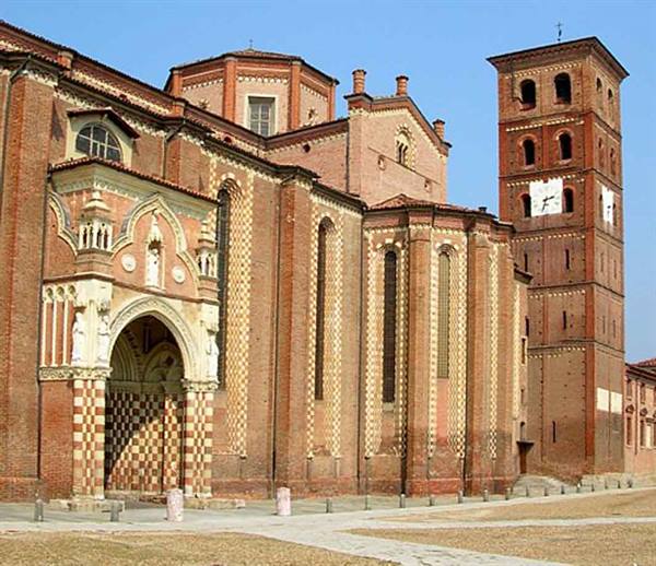 Brick church with checkered facade and tall bell tower under blue sky