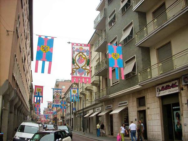 City street with medieval banners hung between buildings, pedestrians and cars