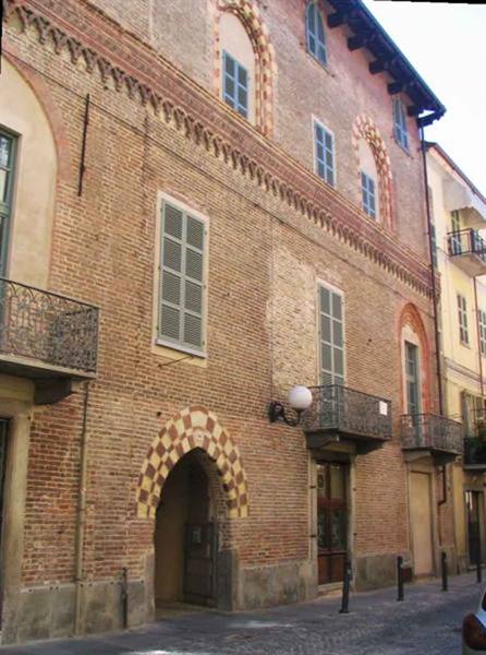 Brick palace with red-and-white patterned archway, wrought-iron balconies, sunny street