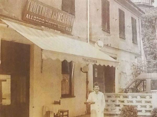 Woman in white apron holding tray outside Trattoria al Merlo, vintage photo