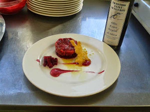 Gourmet plate with red tartare and raspberry sauce beside extra virgin olive oil