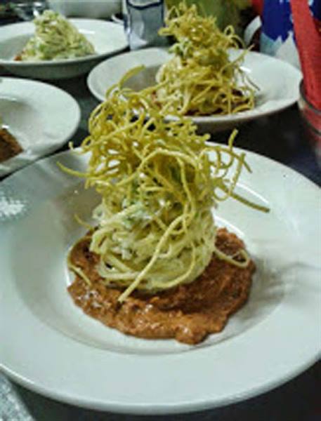 White plate with spaghetti cream and crispy noodles over red sauce