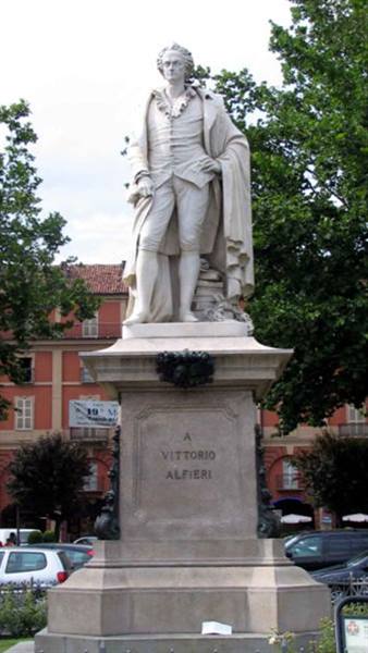 Marble statue of Vittorio Alfieri on stone pedestal, tree-lined square with buildings