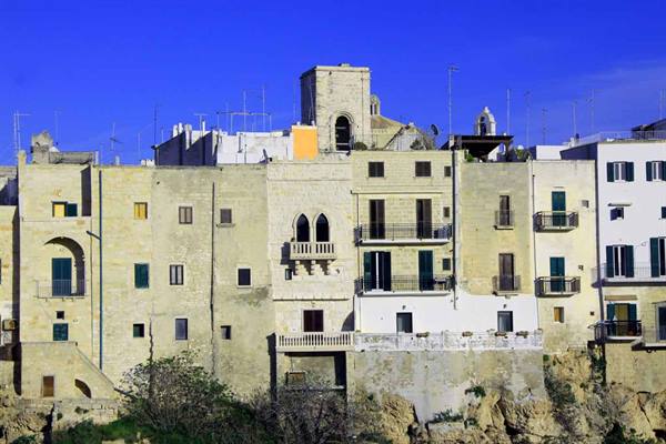 Old limestone houses with balconies rise above the cliffs in Polignano a Mare