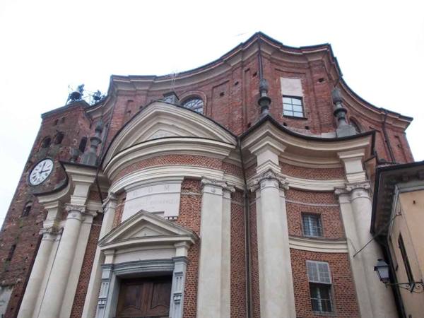 Baroque brick church with curved facade, pale columns and clock tower