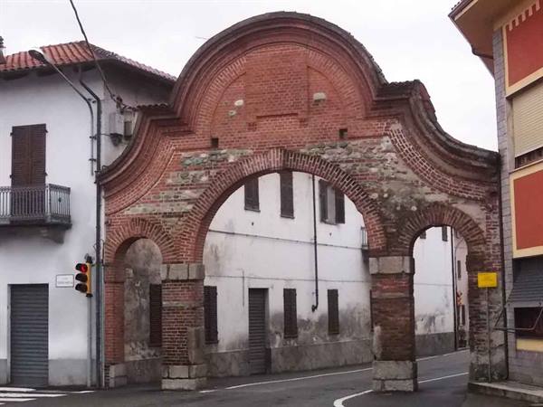 Old red brick double-arch gateway across a street between houses