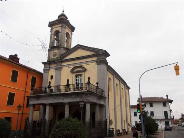 Yellow church with columned portico and bell tower, green traffic light, gray sky
