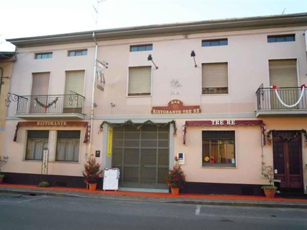 Pink facade of Tre Re restaurant with sign, burgundy awnings and garland-decorated balconies