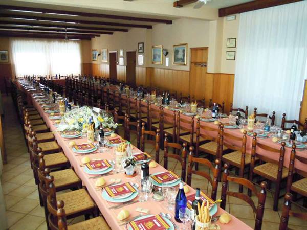 Dining hall with long set tables, wooden chairs and pink tablecloths