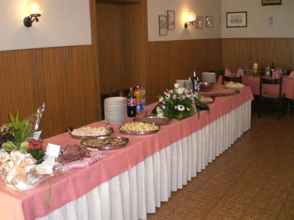 Buffet table with pink tablecloth, food trays, flowers and plates in dining room