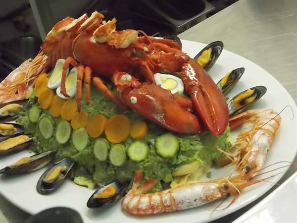 Seafood platter with lobster, mussels, prawns and vegetables on green purée