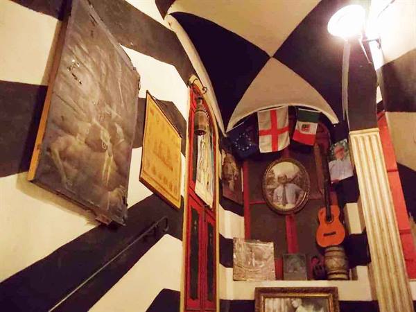 Interior with black and white striped walls, paintings, flags and an orange guitar