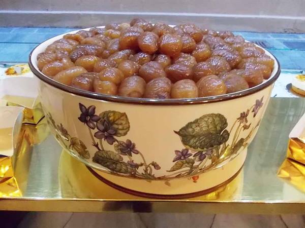 Ceramic bowl decorated with violet flowers filled with glossy candied chestnuts