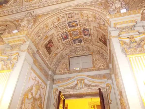 Frescoed vault above doorway, gilded stuccoes and framed paintings