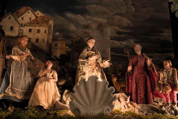 Nativity scene with fabric and plaster figures, baby Jesus in illuminated shell