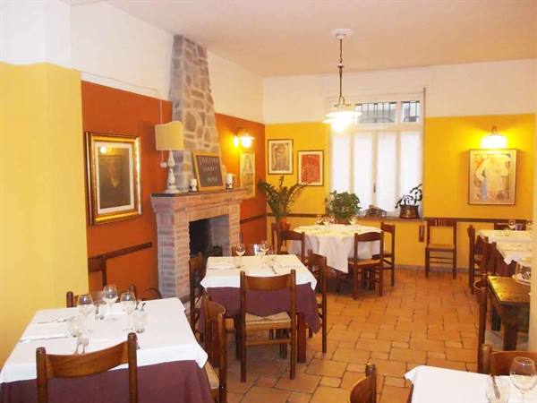 Trattoria dining room with set tables, stone fireplace and yellow walls