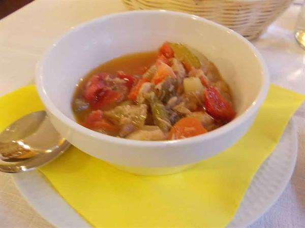 Vegetable soup in white bowl, yellow napkin, warm restaurant lighting