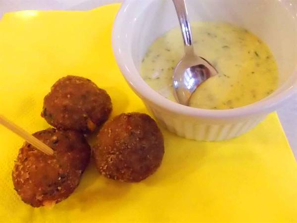 Fried meatballs on toothpicks with creamy dipping sauce in white bowl