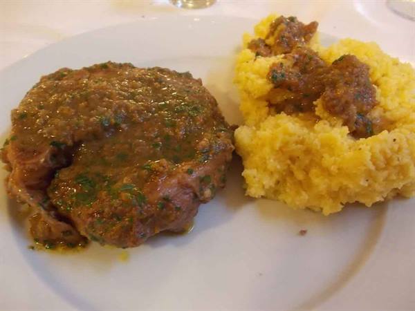 white plate with meat in sauce and yellow polenta