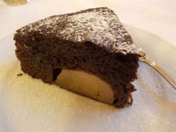 Chocolate pear cake dusted with powdered sugar on a white plate