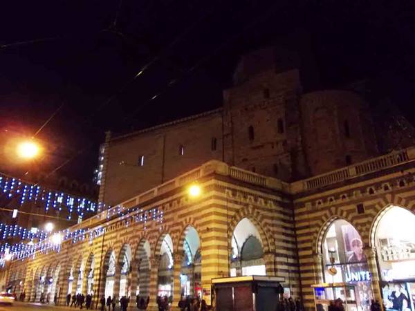 Striped black and white arcades lit at night in Genoa