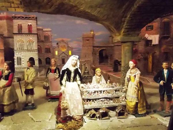 Nativity scene figurines in traditional costumes around a statuette stall