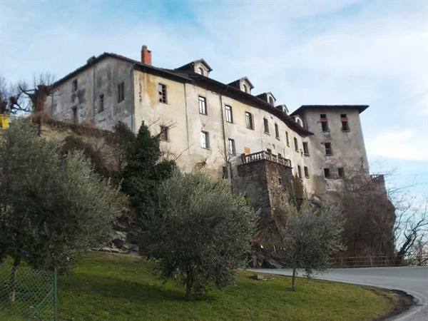Old abandoned stone building with peeling plaster among olive trees