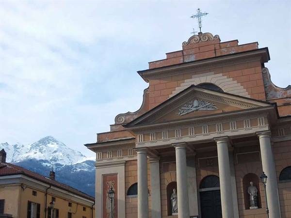 Church with columns and cross in front of snowy mountains