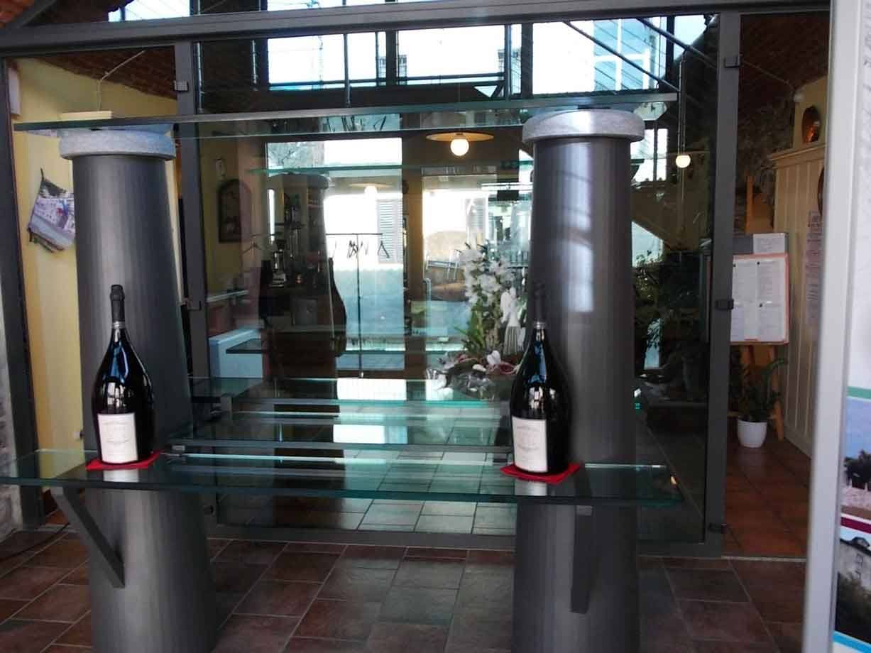 Due grandi bottiglie di vino su mensole di vetro tra colonne metalliche