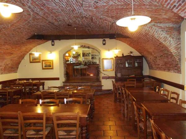 Tavern with brick vaulted ceilings, wooden tables and central bar counter