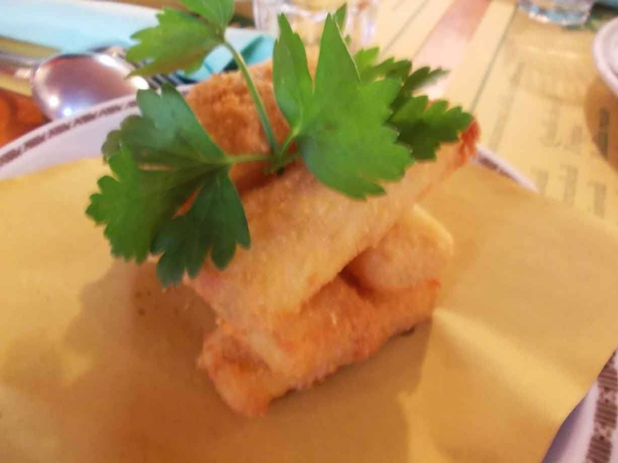 Mozzarella fritta dorata impilata su carta gialla, guarnita con prezzemolo fresco