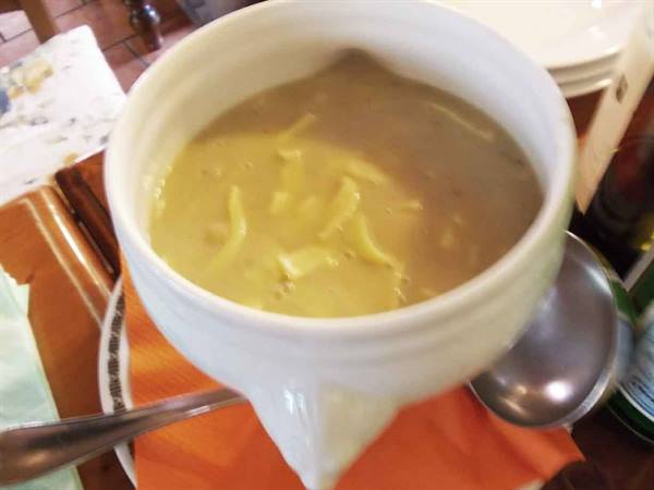 Potato and bean soup in white ceramic bowl, warm restaurant lighting