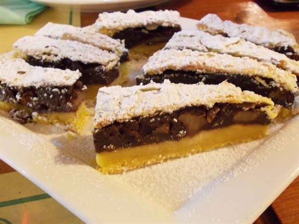 Slices of chocolate and pear tart on white plate, dusted with icing sugar