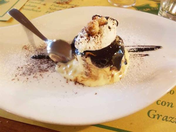Dessert with cream, chocolate and hazelnuts on white plate in trattoria