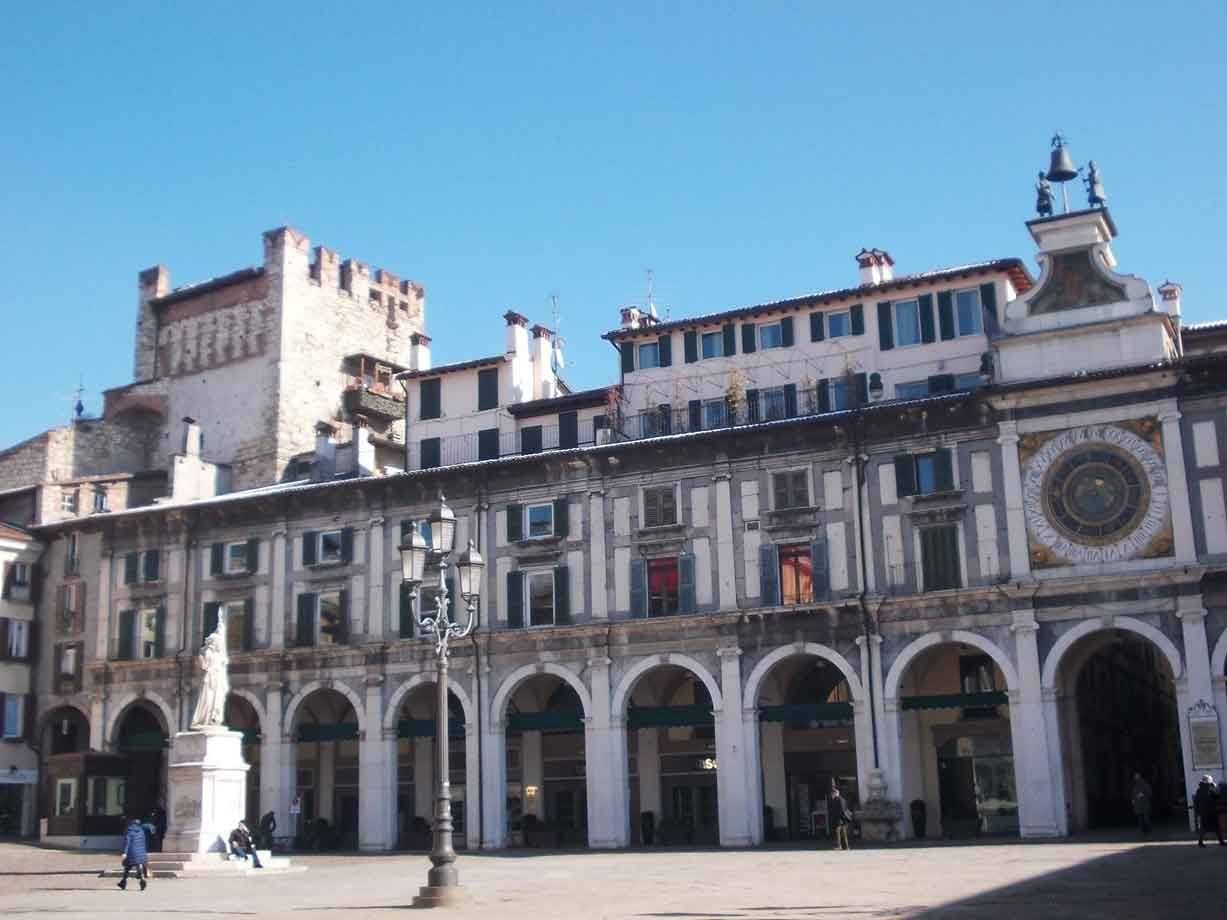 Piazza della Loggia a Brescia con orologio astronomico, portici bianchi e statua