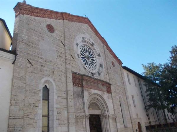 Stone facade of San Francesco church in Gubbio, rose window under blue sky