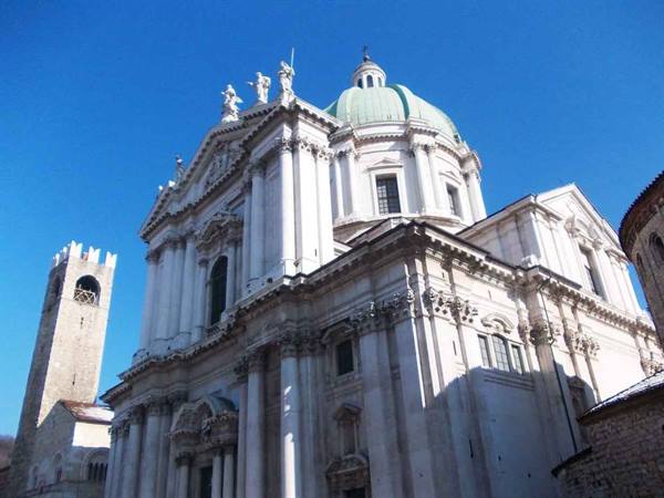 Green dome of Como Cathedral above its white marble baroque facade