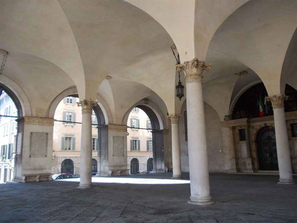 White marble columns support the loggia vaults, daylight over the square