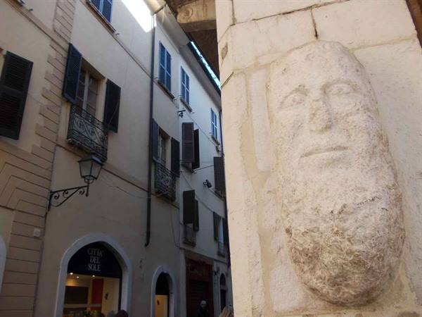 Bearded face carved in stone at the corner of an alley near Grotta del Sole sign