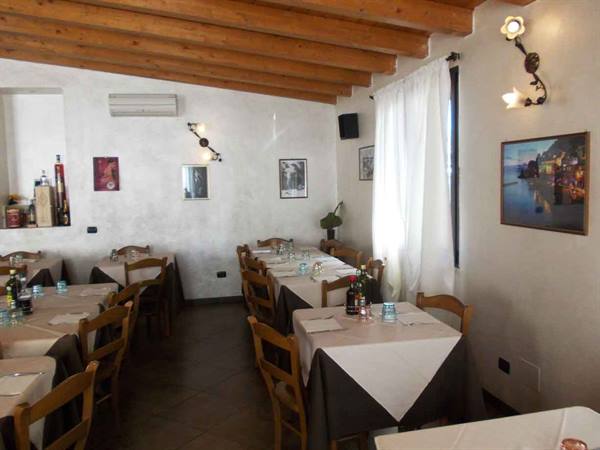 Restaurant dining room with set tables, white tablecloths, wooden ceiling beams and white walls