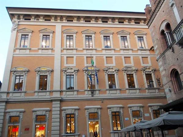 Historic ochre building with flags and café umbrellas on a square