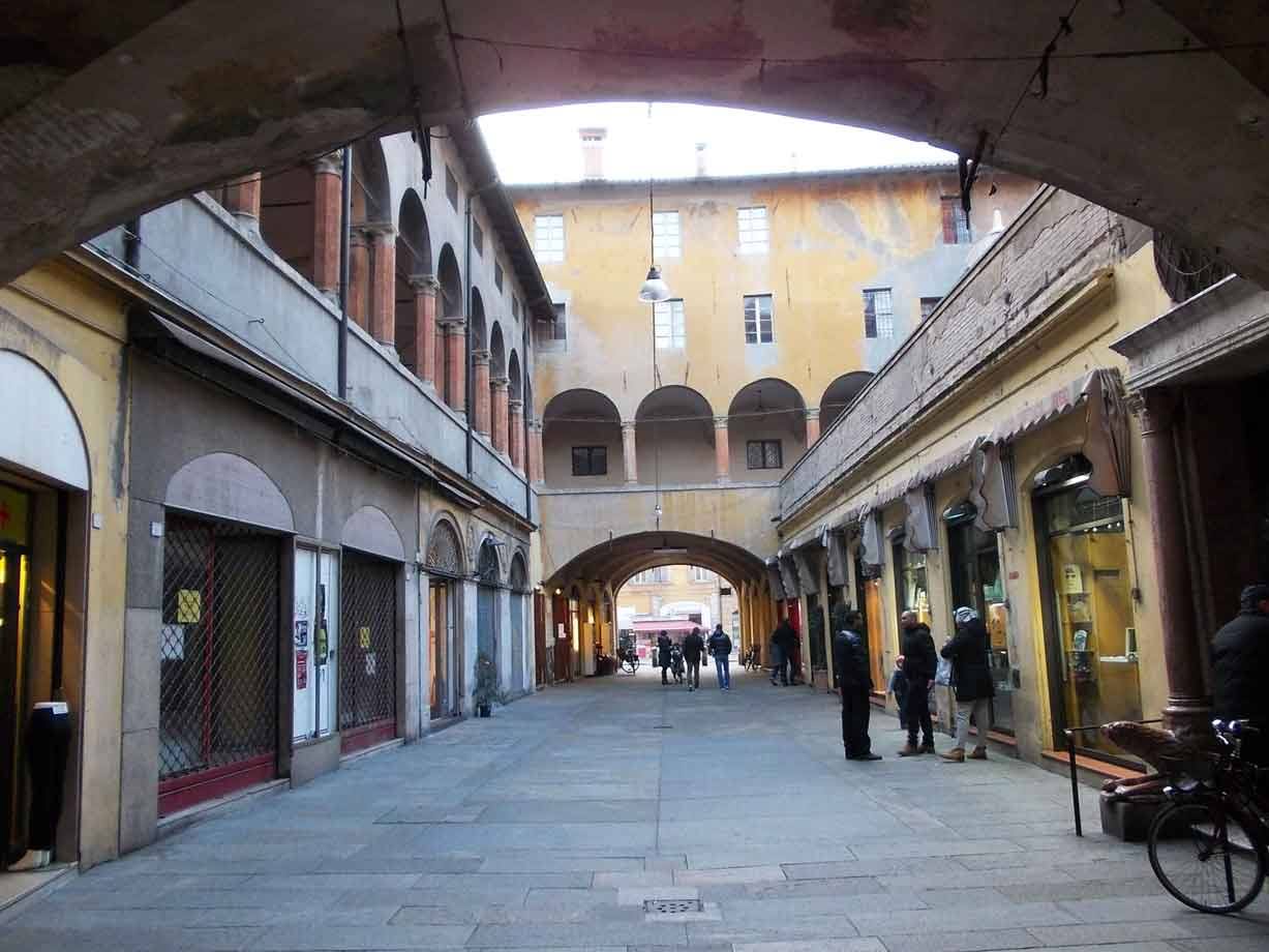 Portico medievale di Bologna con archi in mattoni, passanti e bicicletta