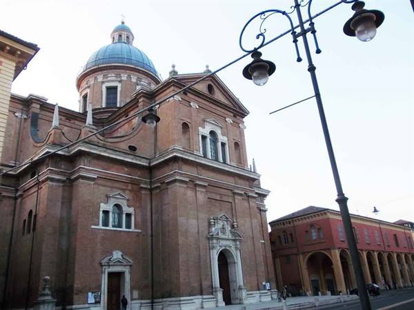 Brick church with grey dome and marble portals, wrought-iron lampposts, pale sky