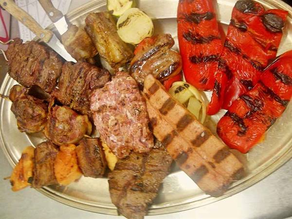 Metal platter with mixed grill: meat, skewers, roasted red peppers and vegetables