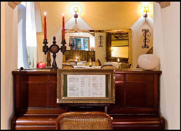 Wooden piano with red candles and framed menu in a restaurant