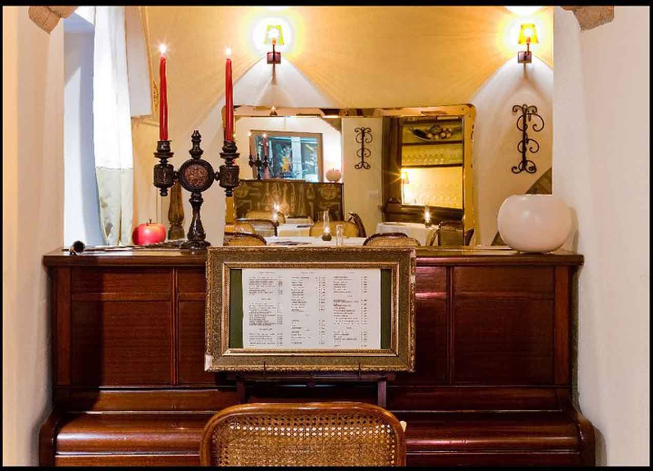Pianoforte in legno con candele rosse e menu incorniciato in un ristorante