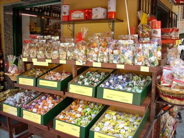 Candy stall with wrapped sweets in green boxes outside a small shop